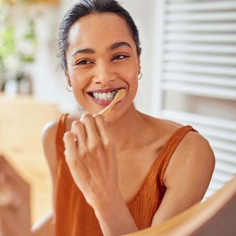 Woman smiling while brushing her teeth