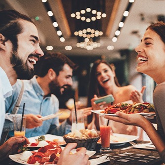 Group of friends smiling while eating at restaurant